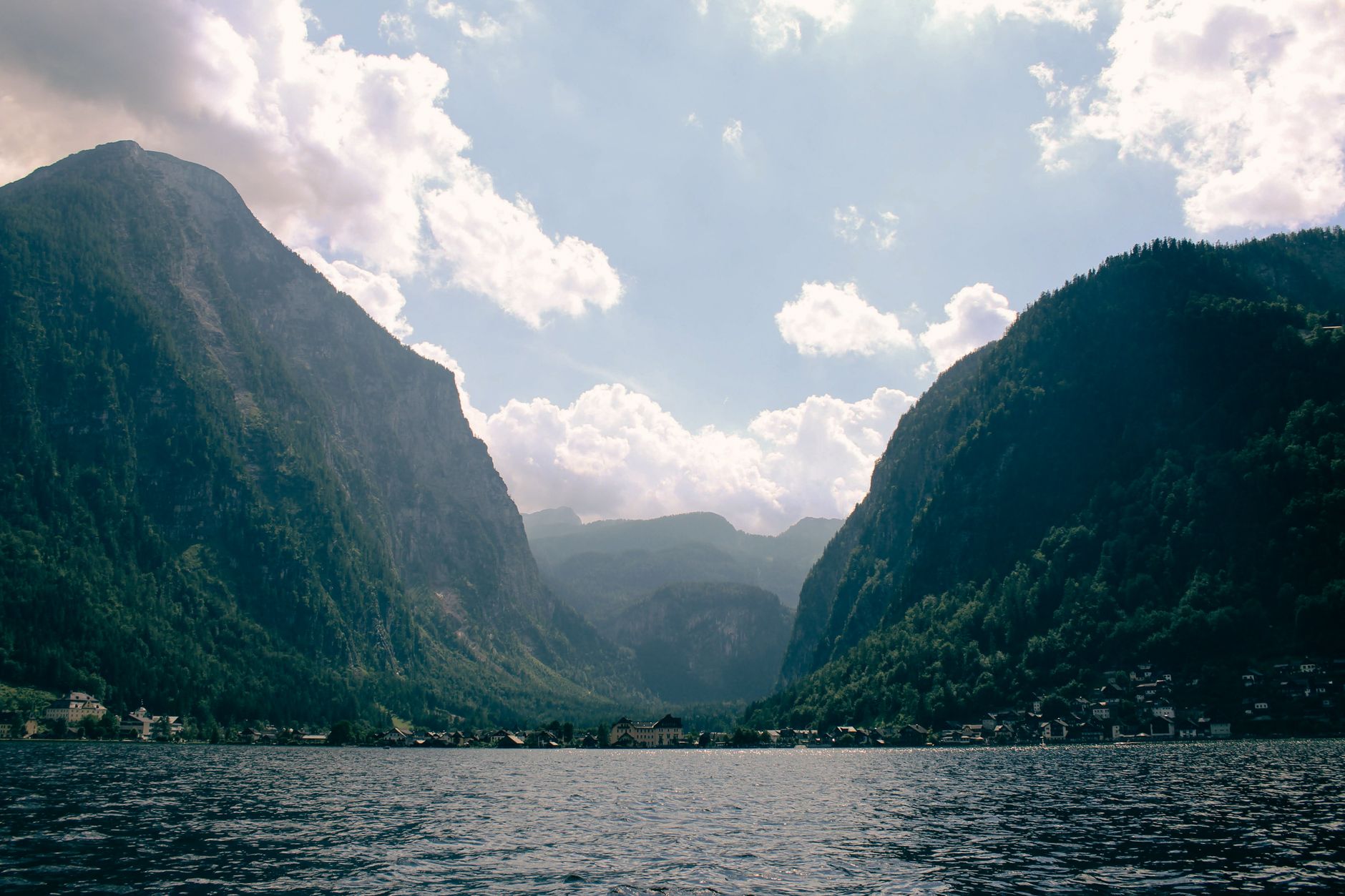 Scenic landscape of Hallstatt's towering mountains and tranquil lake under a cloudy sky.
