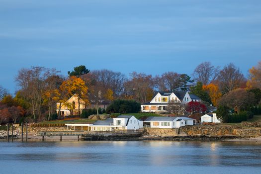 Waterfront homes in Stamford, Connecticut, during a calm autumn sunrise, showcasing vibrant fall colors.