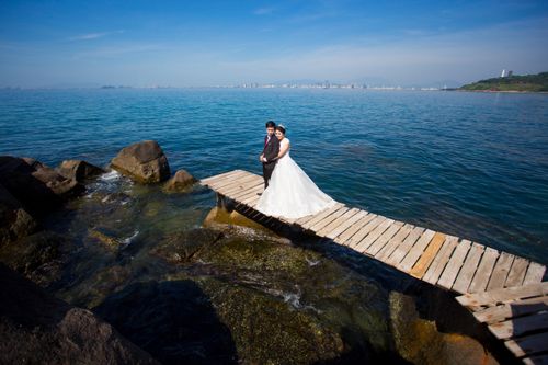 Free Bride and groom pose on a rustic pier by the sea in Hội An, Vietnam. Stock Photo