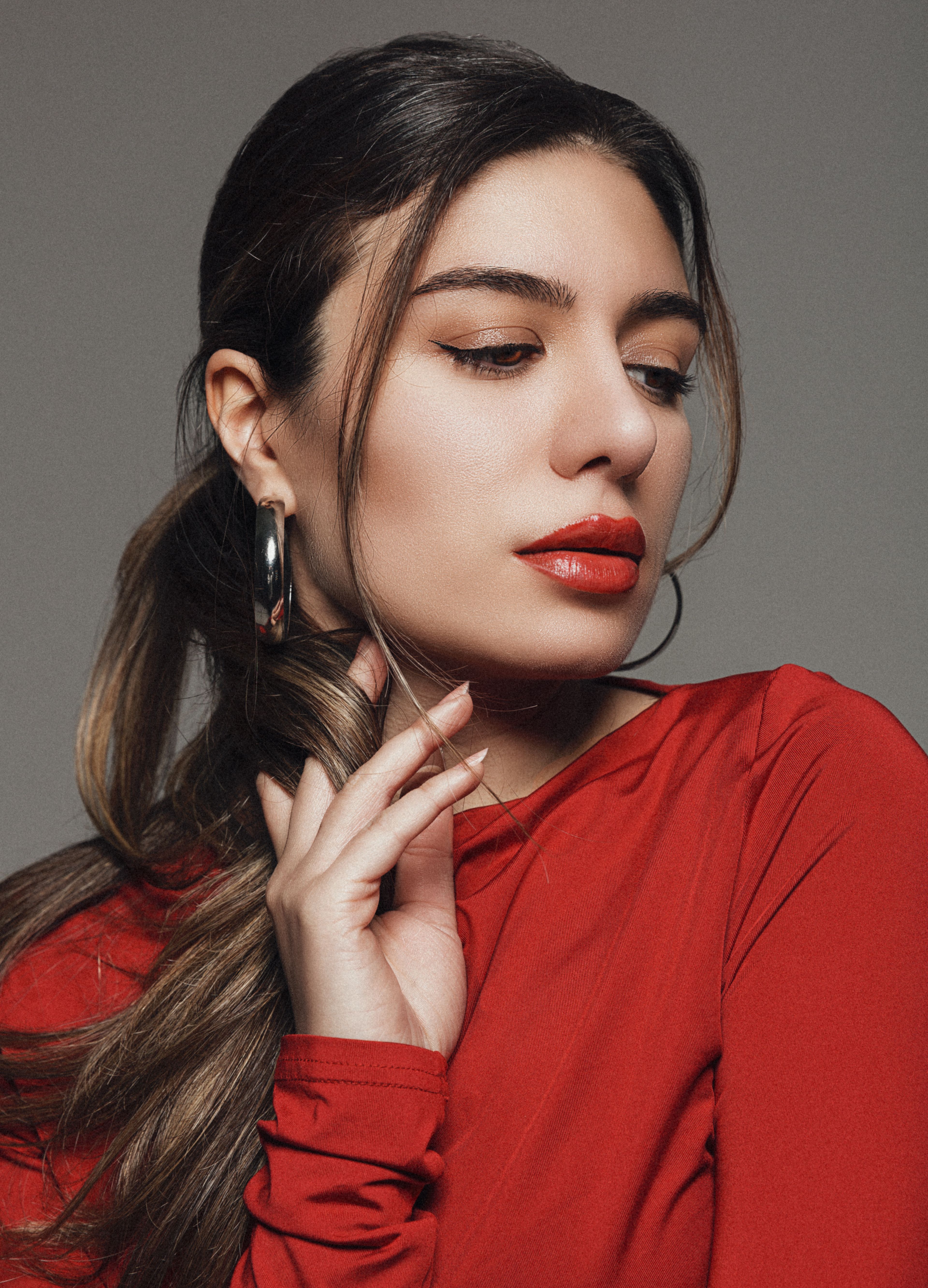 Elegant close-up portrait of a woman with red lipstick and hoop earrings.