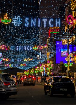 Colorful street decorated with festive lights and cars driving at night.