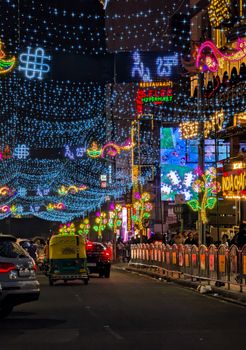 A bustling street decorated with colorful festive lights during the night.