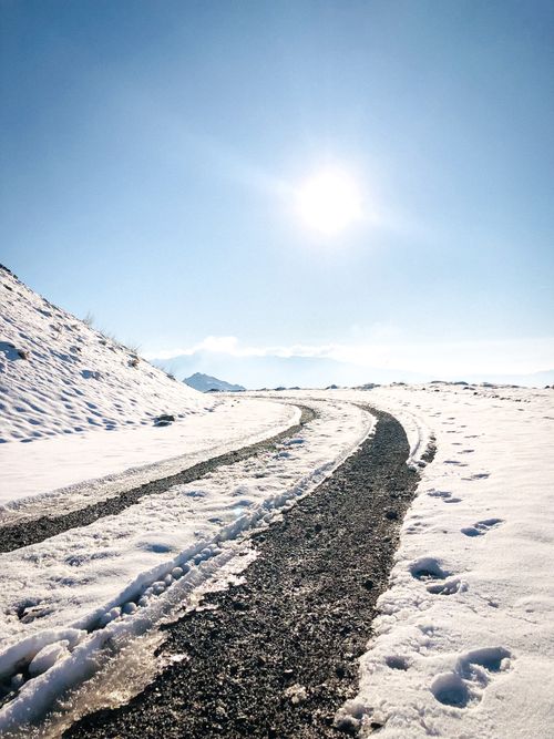 Free Curved road cutting through snowy mountains under a bright winter sun. Stock Photo