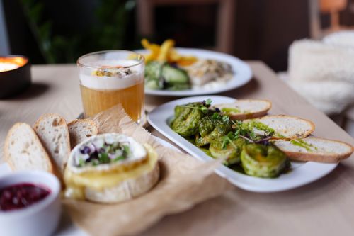 Free Delicious vegetarian dish with bread, cheese, and greens on a wooden table. Stock Photo