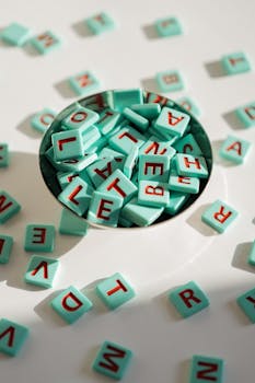 A collection of colorful letter tiles spilling from a metal bowl, arranged creatively.