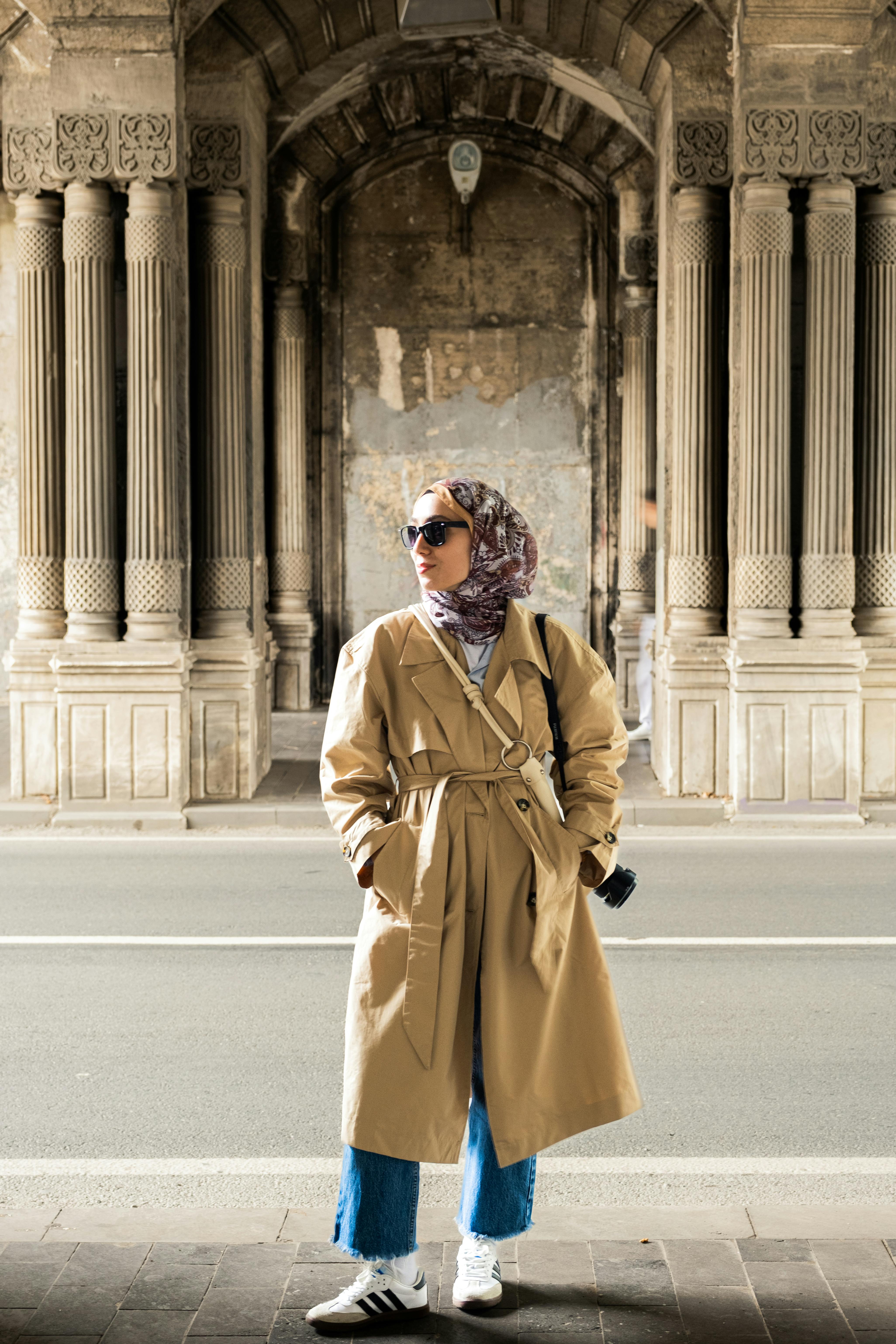 A fashionable woman in a trench coat exploring historic İstanbul architecture.