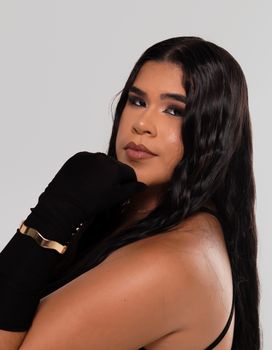 Portrait of a young woman with long hair wearing black gloves and looking confidently at the camera.