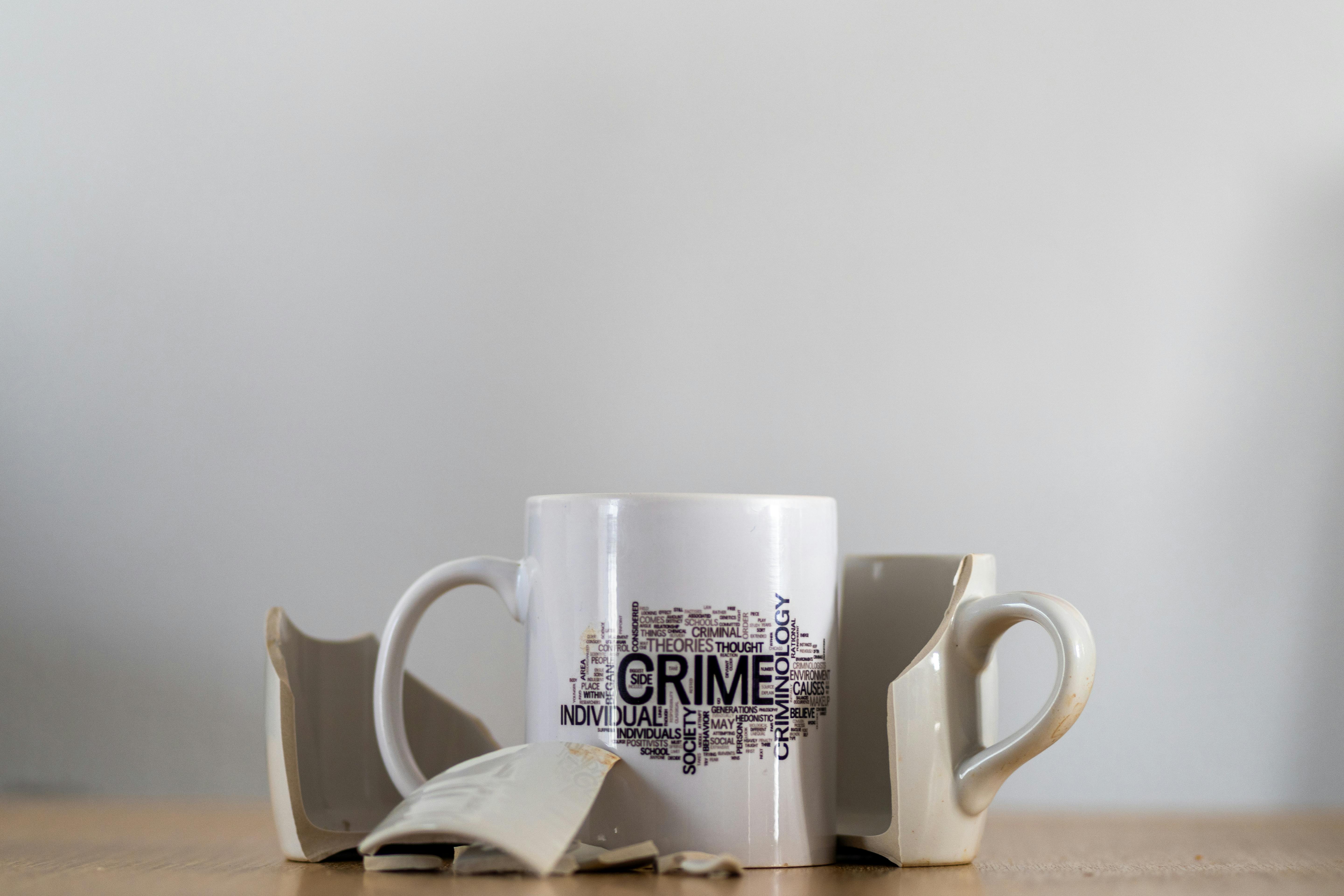 Artistic photo of a broken coffee cup featuring crime-related word art.
