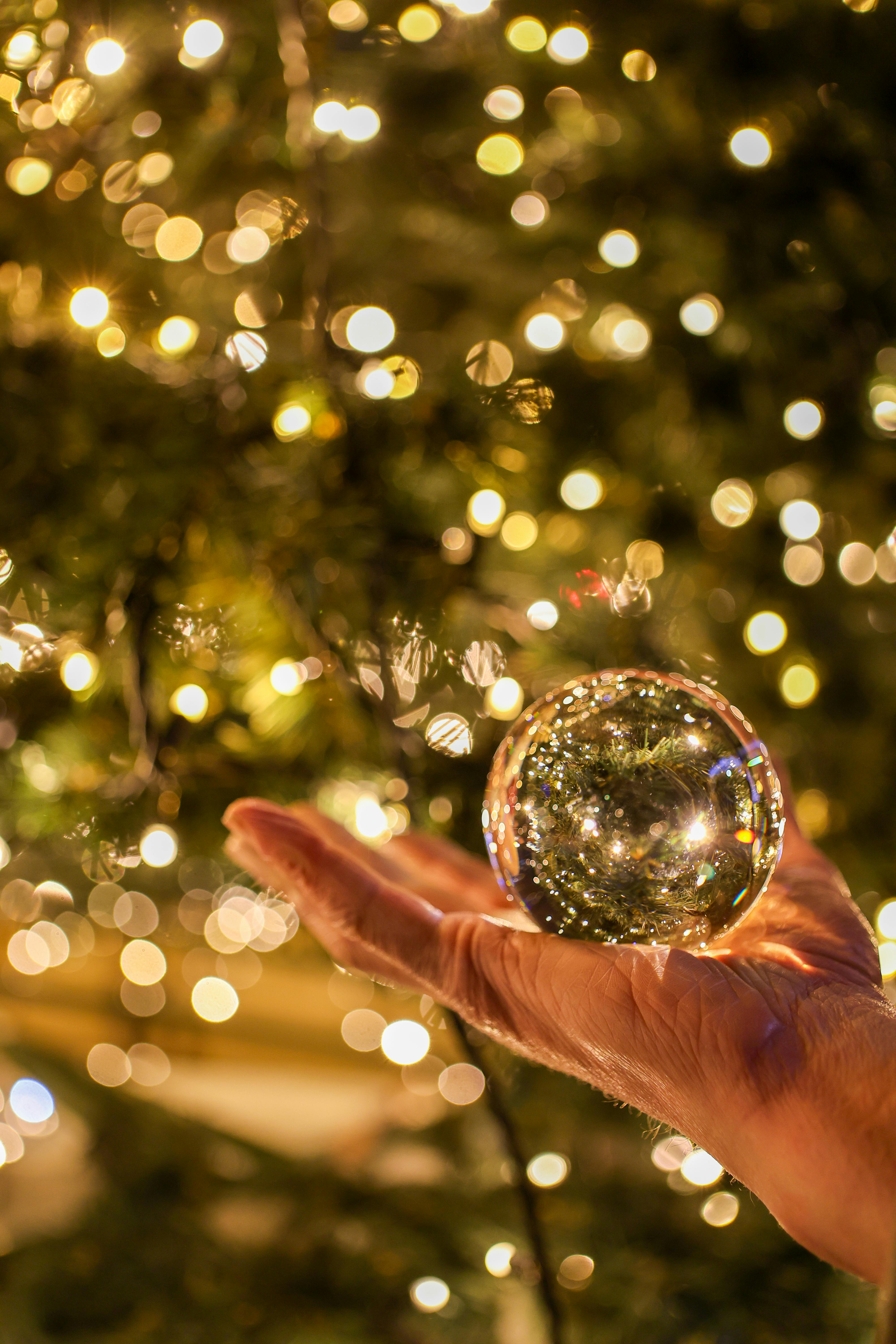 festive hand holding glass sphere with bokeh