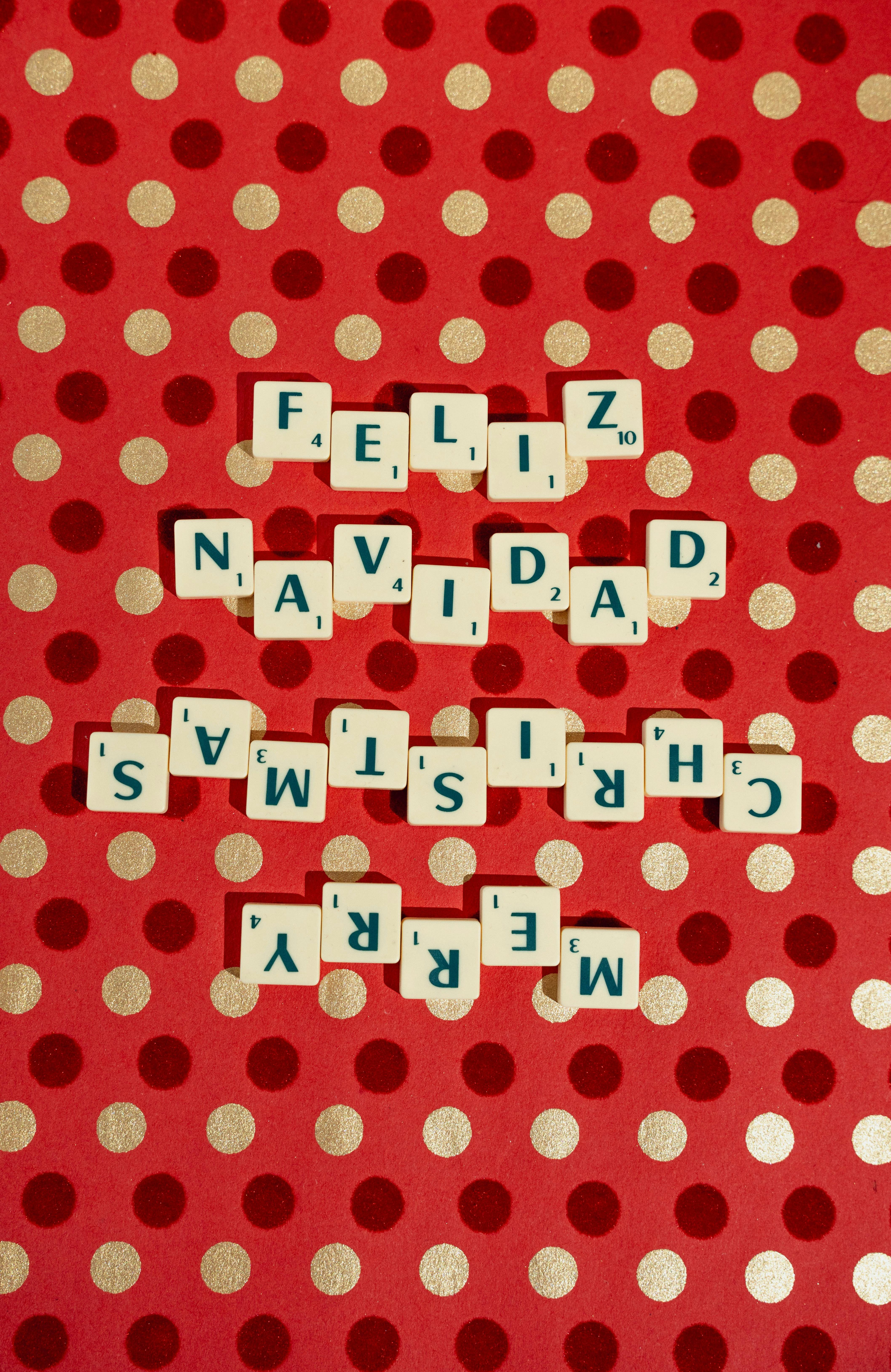 Gratis Fichas de Scrabble que escriben Feliz Navidad y Merry Christmas en papel festivo de lunares rojos. Foto de stock