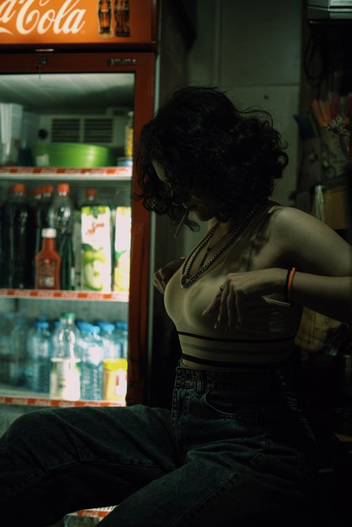 Free A woman stands near a fridge, dimly lit, creating a moody ambiance. Stock Photo