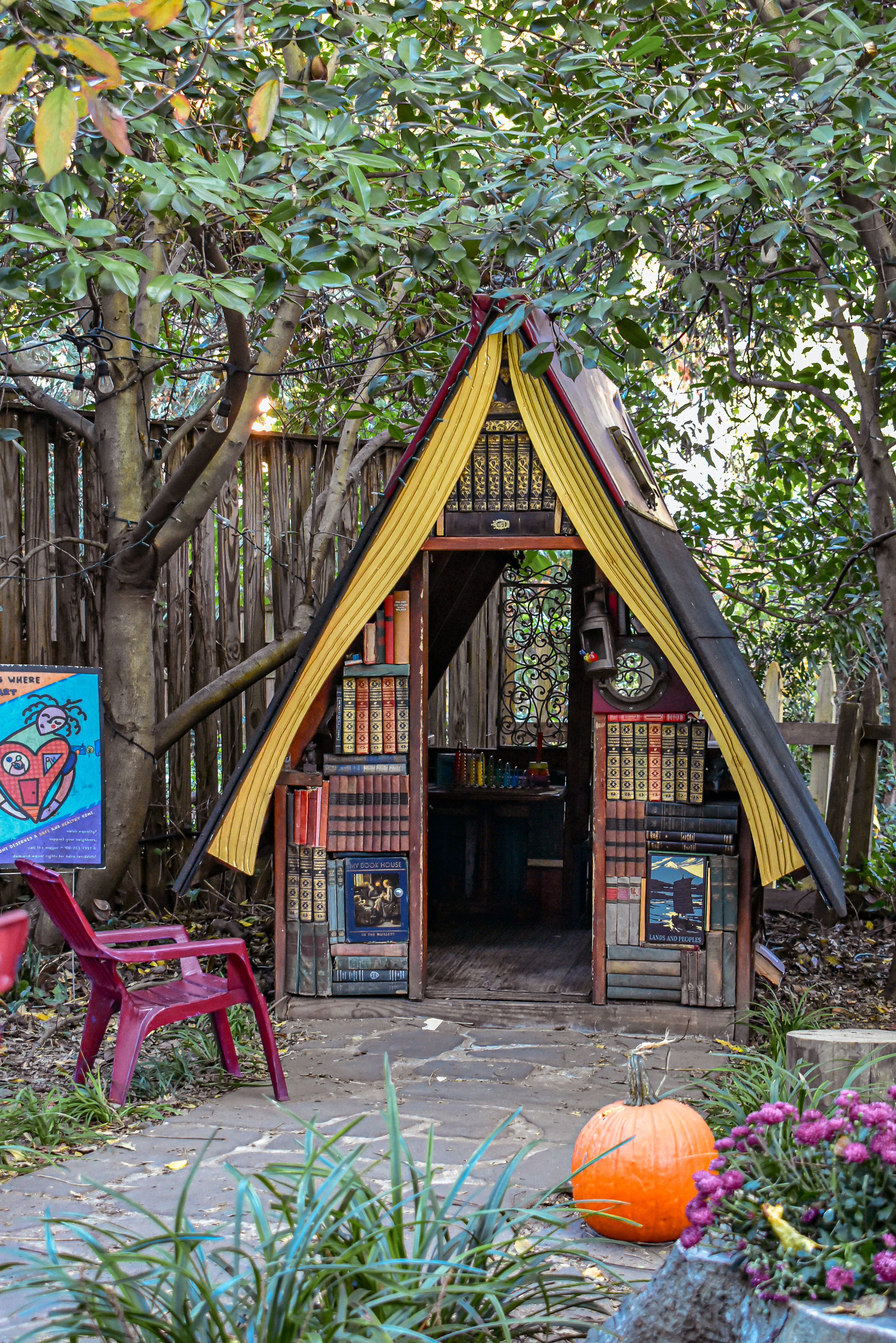A whimsical A-frame house made of books in an Annapolis garden with autumn colors.