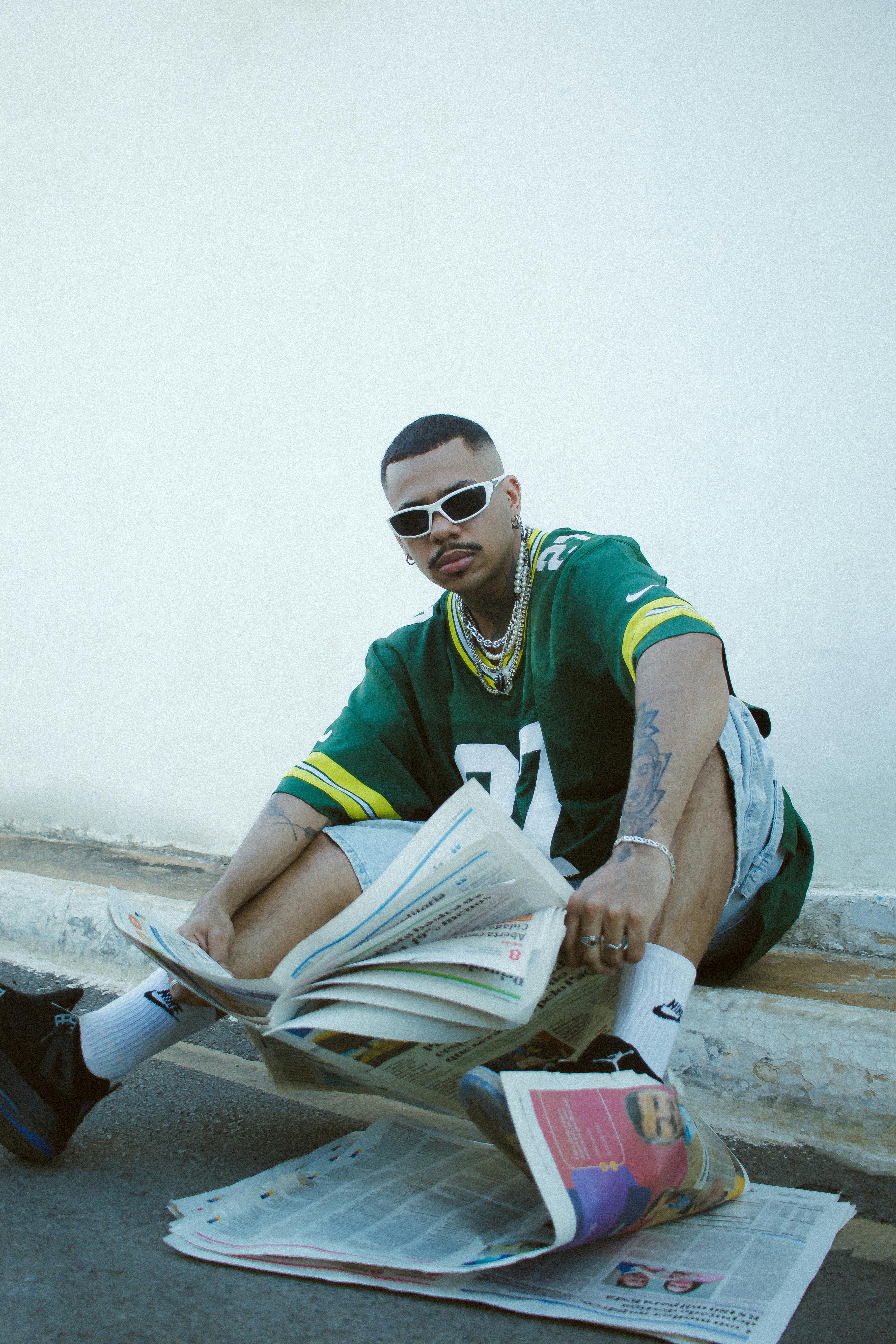 Young man with modern street style reading newspapers outdoors in Barreiras, BA, Brazil.