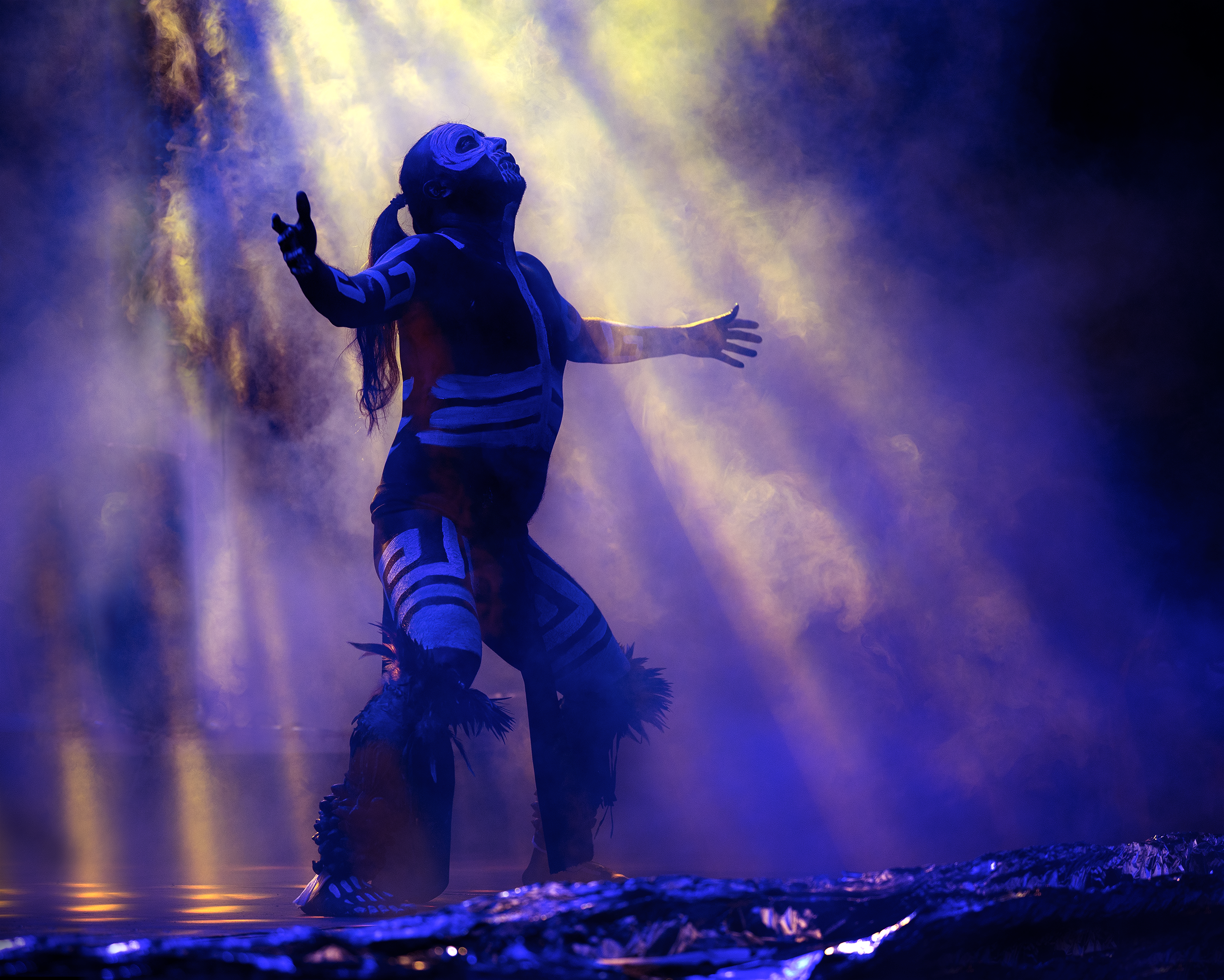 A dancer in indigenous attire performs a mystical ritual under dramatic lighting in Puebla, Mexico.