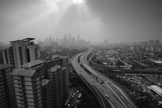 在戏剧性的天空灯光下，高角度的黑白城市景观中可见高速公路与建筑物