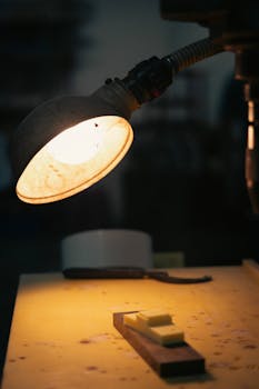 An atmospheric shot of a lit lamp casting light on a workshop table. Perfect for industrial themes.