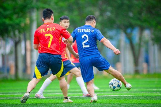 Intense amateur soccer match on a sunny day in Hanoi, showcasing local teams in action.