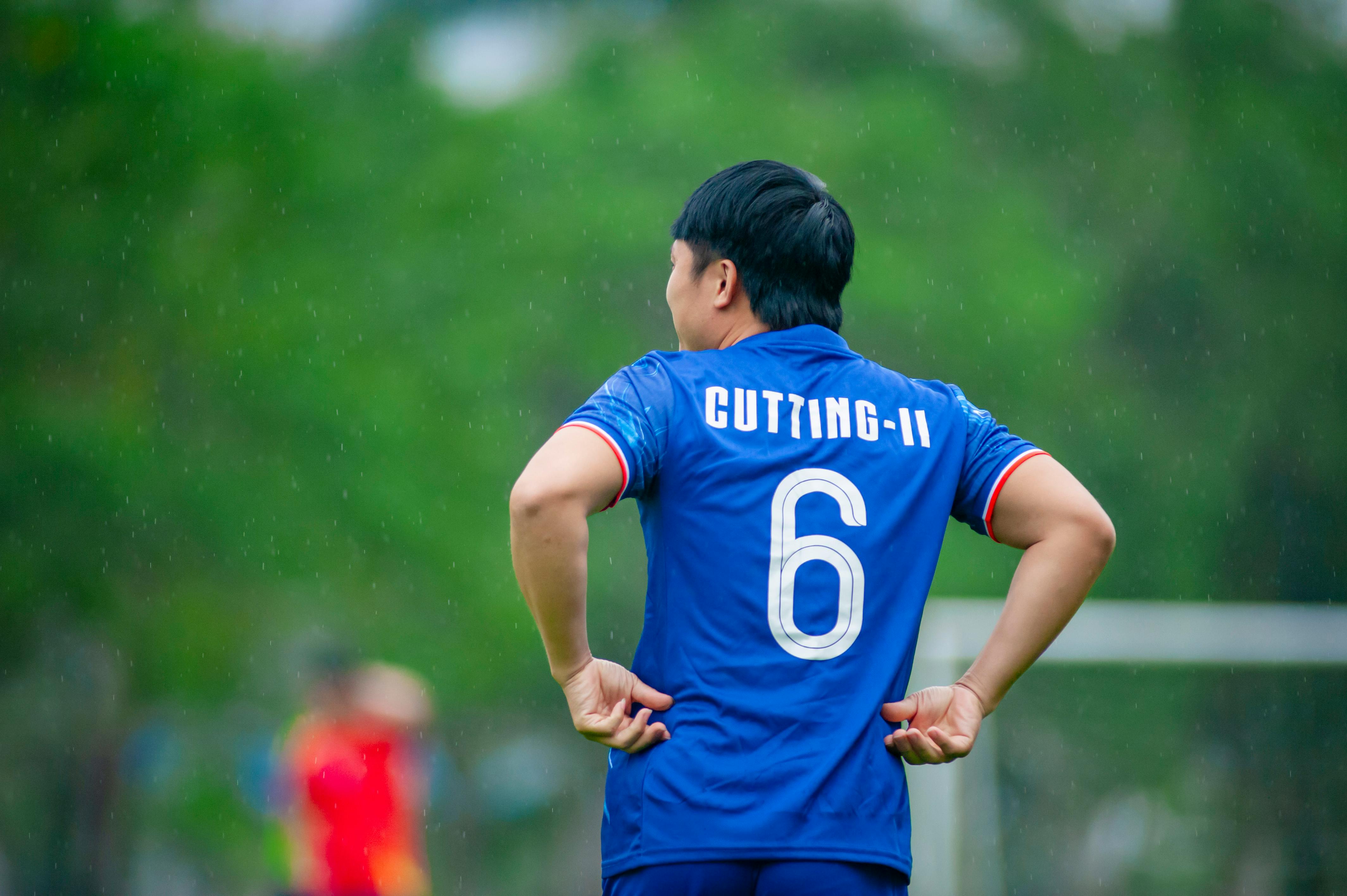 soccer player in blue jersey during rainy match