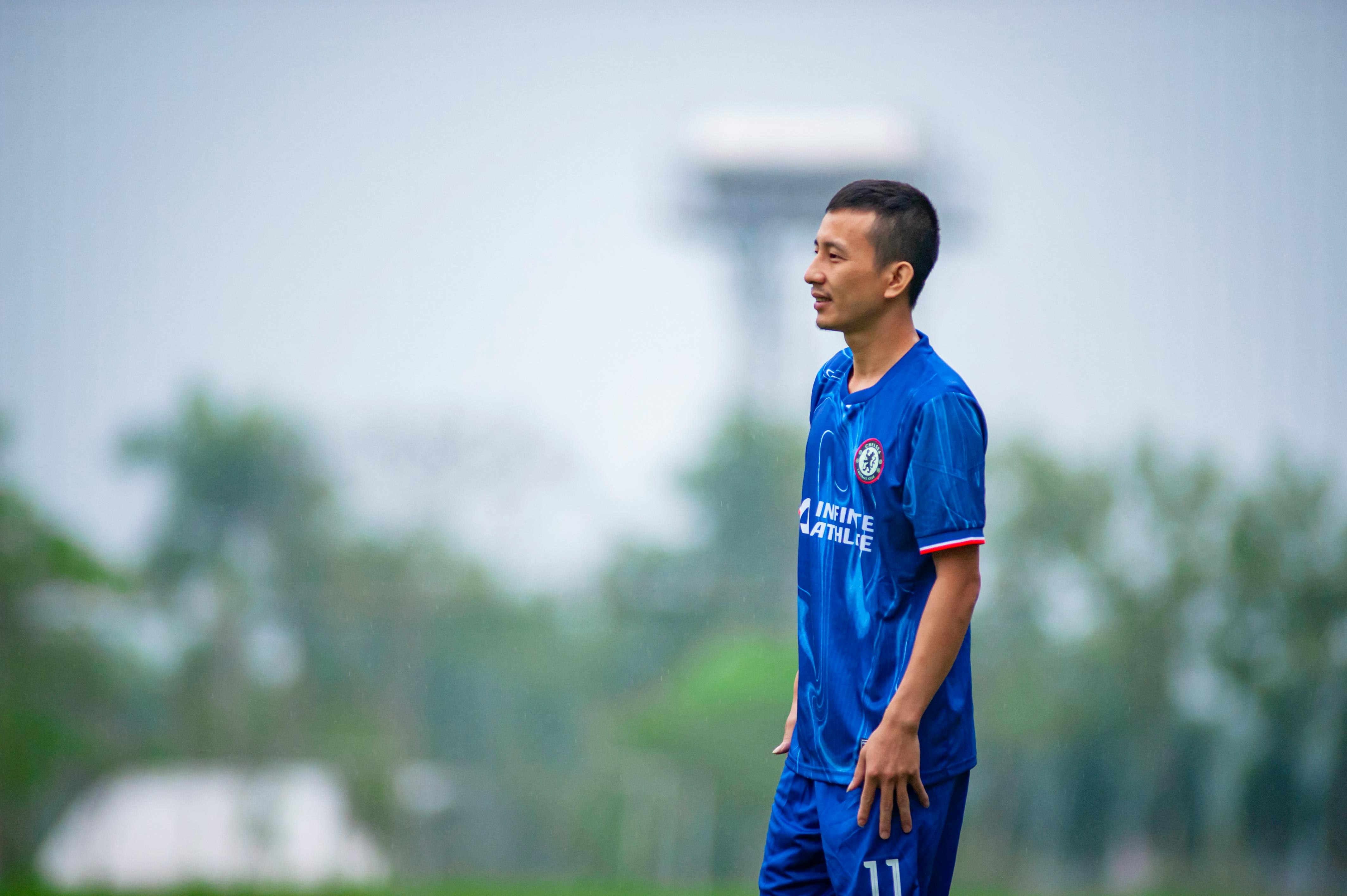 Soccer player in blue uniform on a grassy field in Hà Nội, Việt Nam.