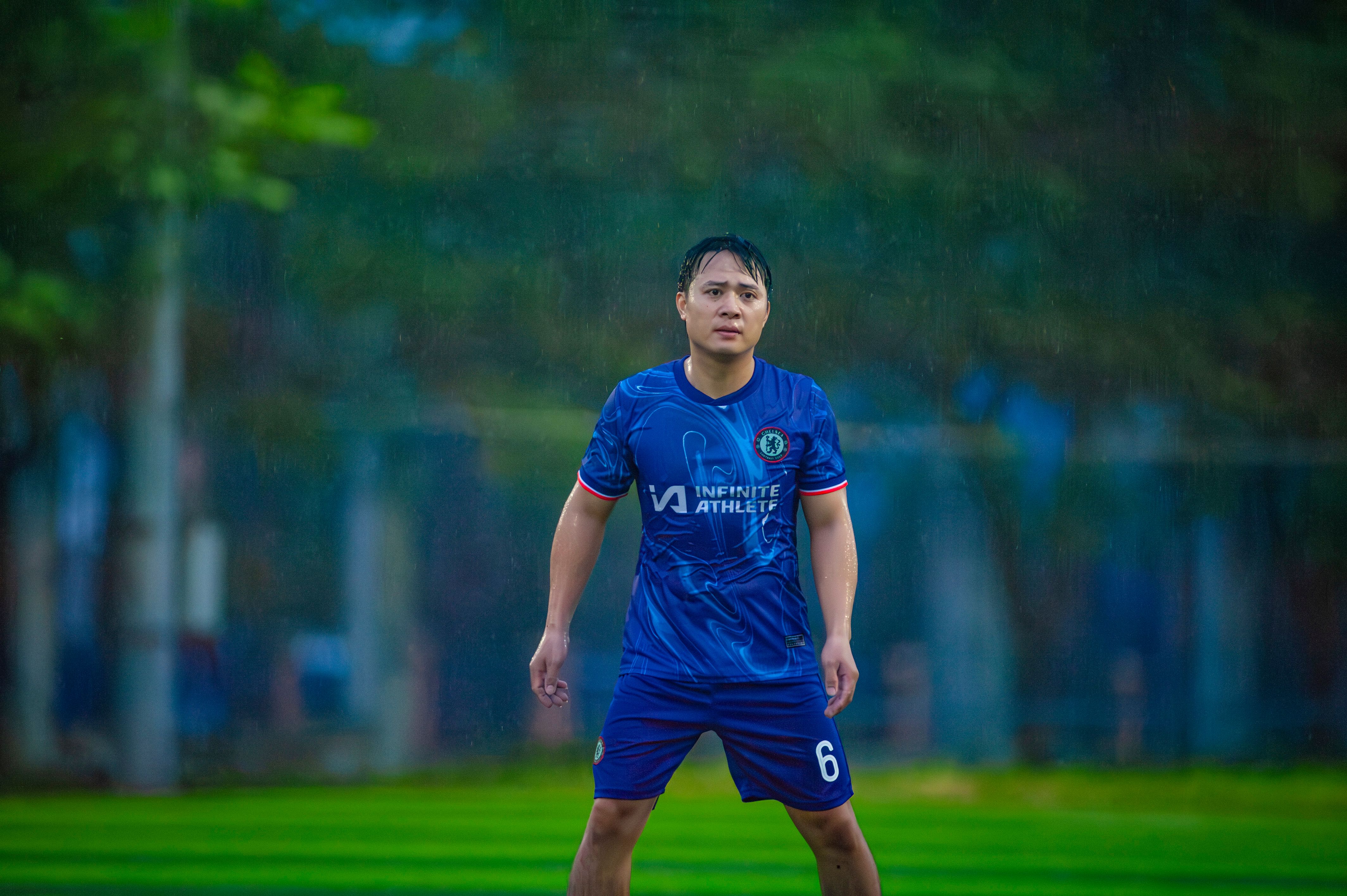 Dynamic shot of a soccer player in action on a rainy field in Hanoi, Vietnam.