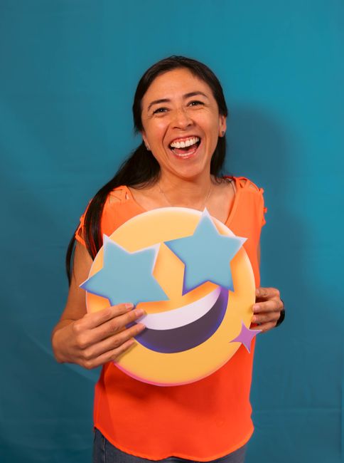 Fotomural Mujer alegre con un cartel de emoji de ojos de estrella, fondo brillante.