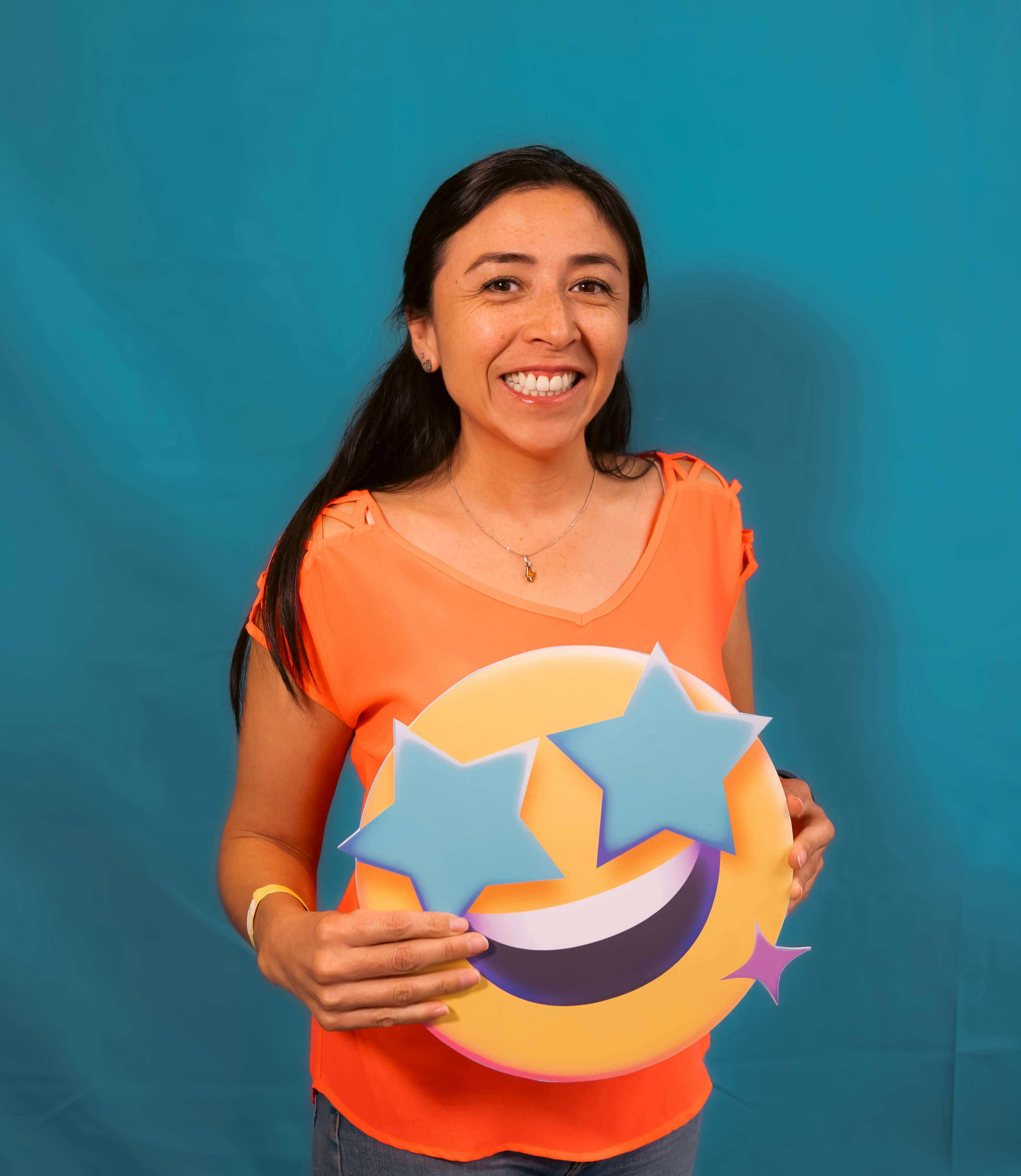 Cheerful woman holding a starry-eyed emoji sign against a blue background.