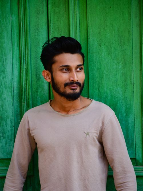 Free Stylish young man with a beard posing against a vibrant green wooden background. Stock Photo