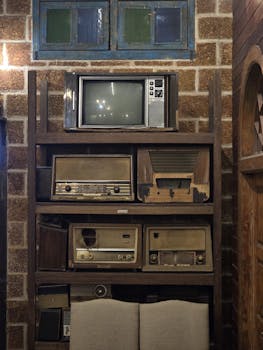 A collection of vintage radios and a TV displayed on rustic shelves, evoking nostalgia.