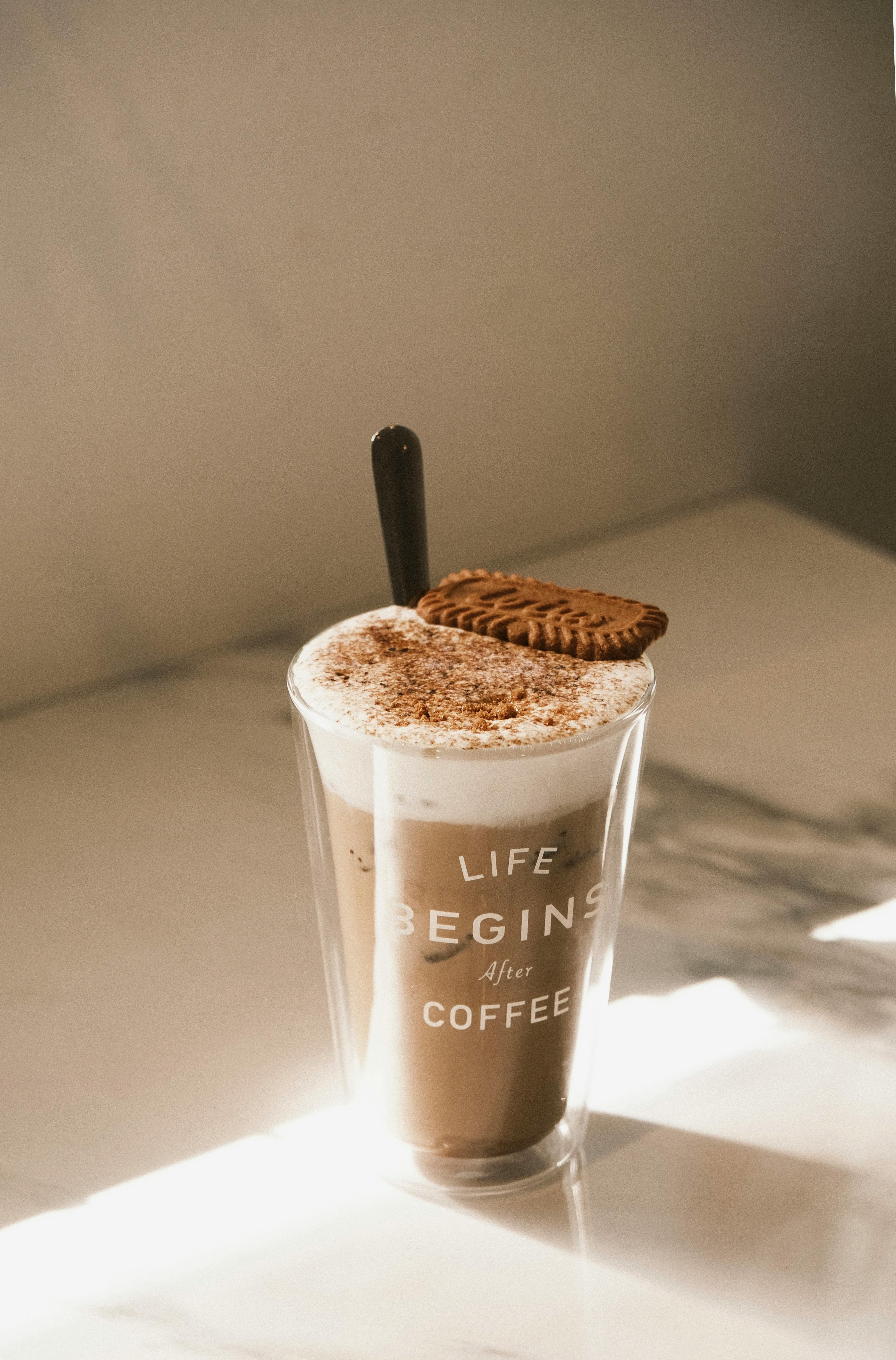 Coffee cup with text and biscuits on a warm lit surface, emphasizing a cozy start to the day.