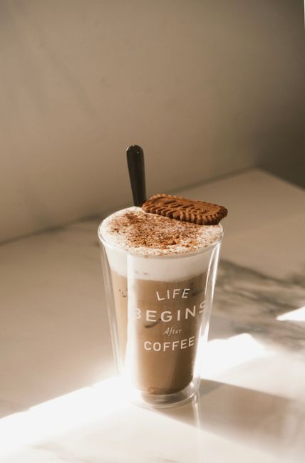 Coffee cup with text and biscuits on a warm lit surface, emphasizing a cozy start to the day.
