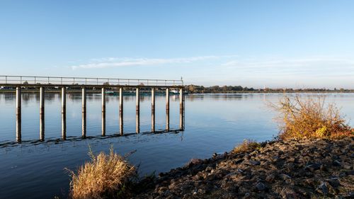 Free Peaceful sunrise view of the Elbe River, Geesthacht with an old bridge reflecting tranquil waters. Stock Photo