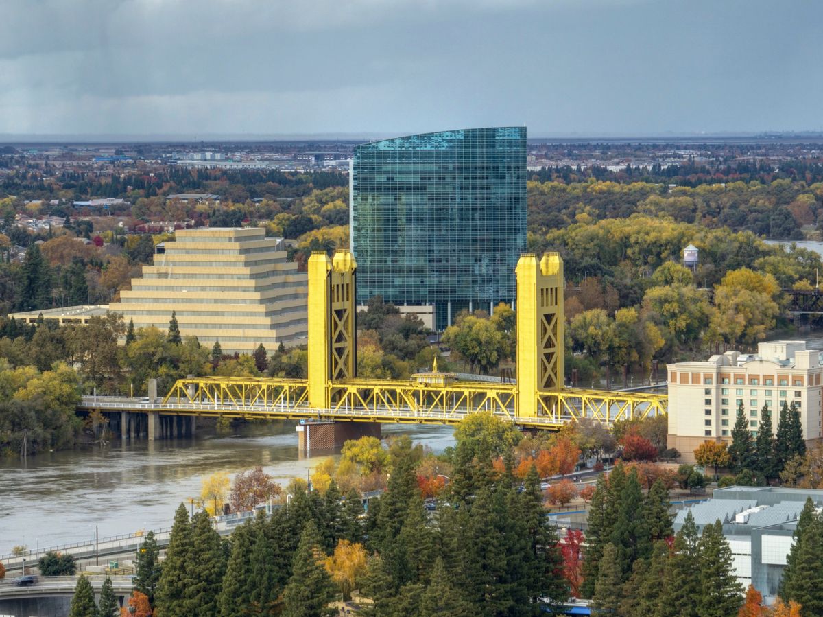 Sacramento's gold Tower Bridge over the river with autumn trees and the downtown skyline behind