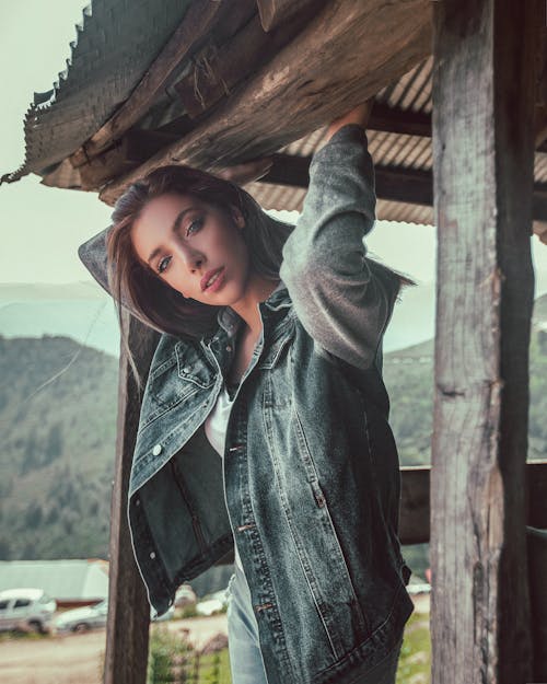 Free Woman Wearing Blue Denim Jacket Standing While Holding On Wooden Slab Stock Photo