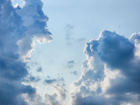 Dramatic cloud formations create a picturesque scene against a clear blue sky, offering a serene atmosphere.