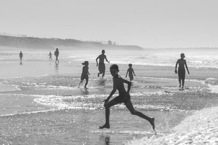 Kids Running From Sea Waves On Coast