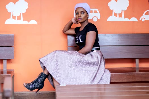 一位穿着时尚服装的优雅女性坐在室内橙色背景的长凳上