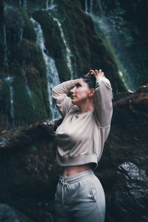 Free Elegant woman poses near a waterfall, embracing nature's beauty and tranquility. Stock Photo