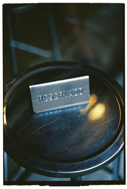 Metal reserved sign placed on a circular metallic table in a dimly lit environment.