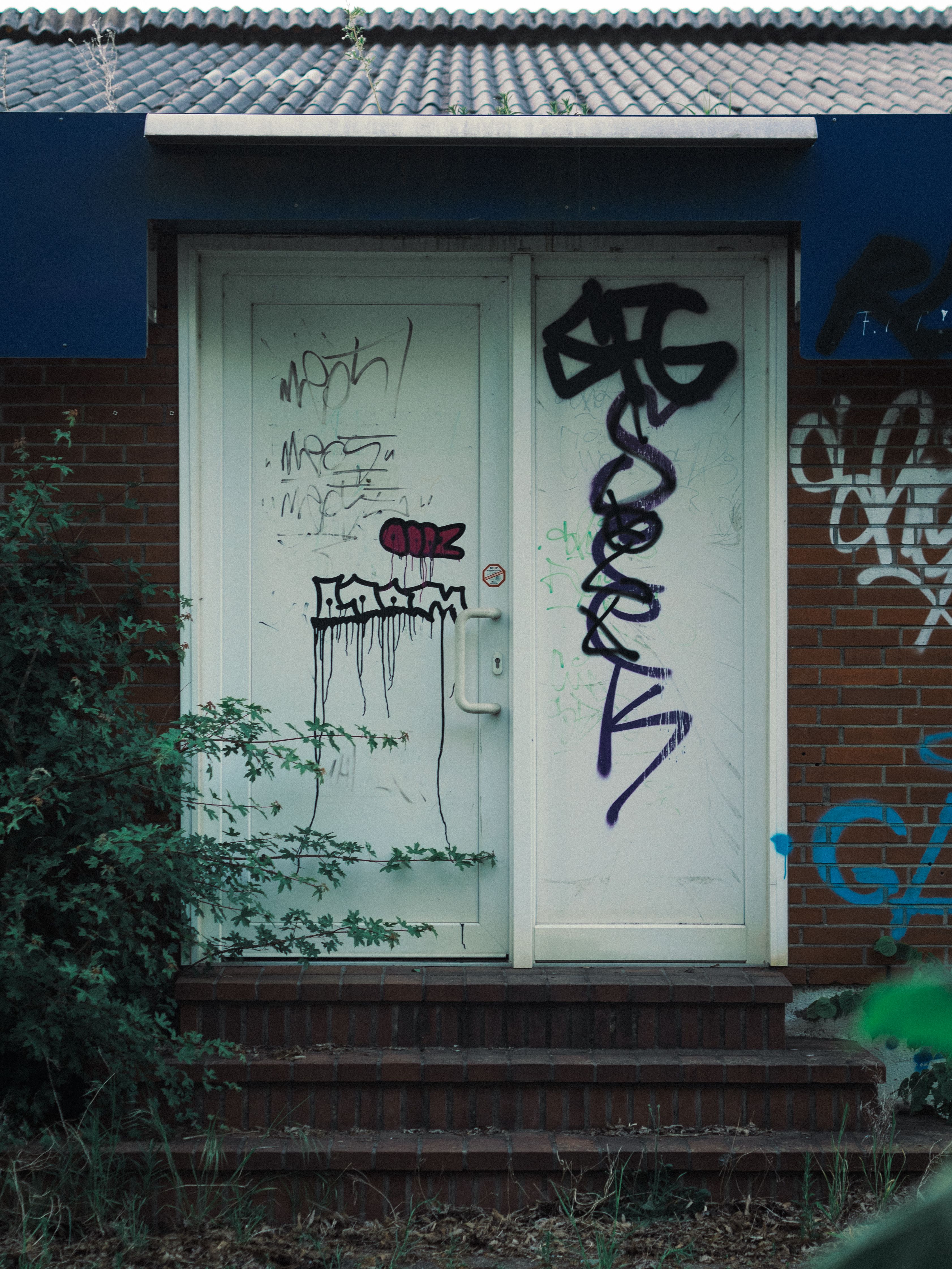 Urban graffiti on a rustic door entrance · Free Stock Photo