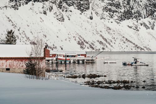 Free Picturesque snowy fishing harbor with sea cliffs and boats in Arctic region. Stock Photo