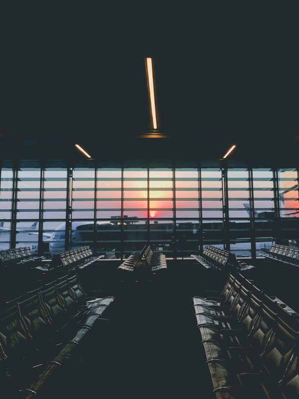 Salão de embarque de aeroporto com aviões ao fundo
