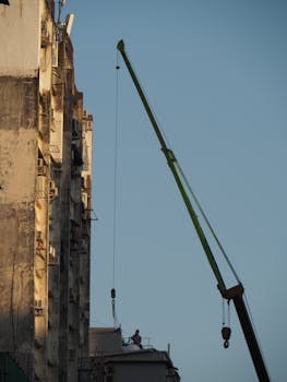 Skyscraper construction in Hong Kong with a prominent tower crane under clear skies.