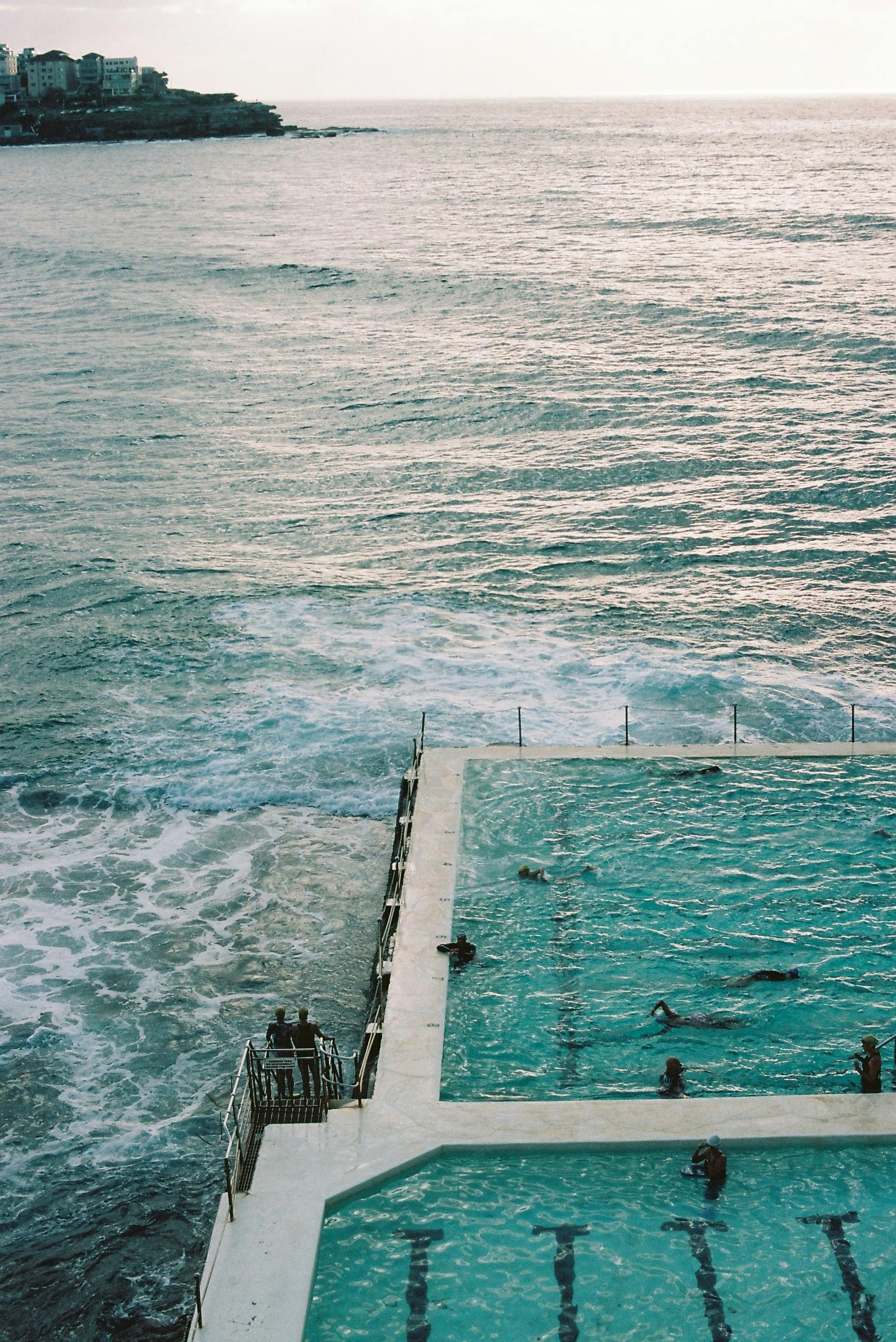 A scenic view of a coastal pool merging with the ocean at sunset, creating a tranquil atmosphere.