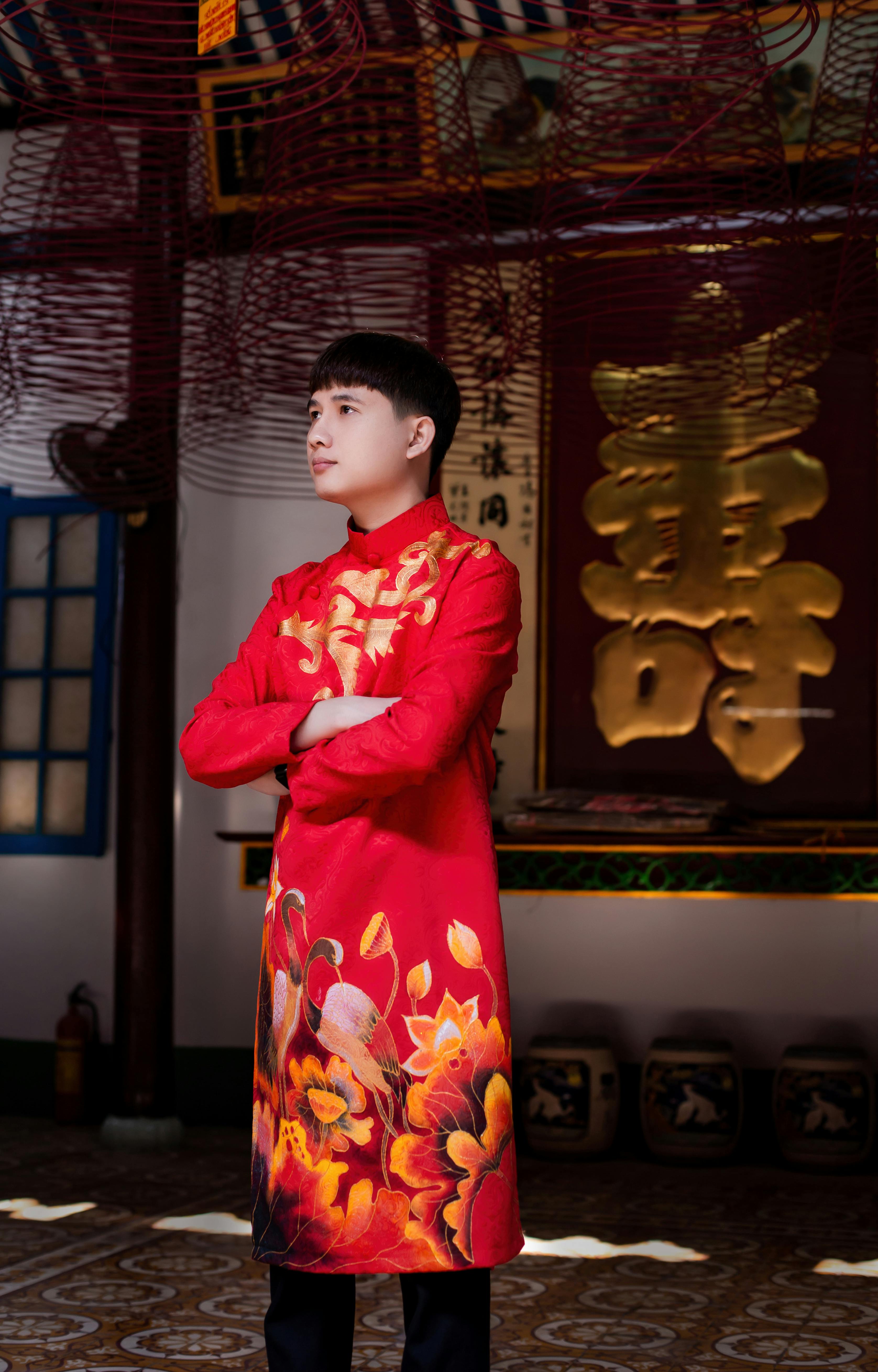 A young adult in a vibrant red Ao Dai stands confidently indoors, capturing Vietnamese culture.
