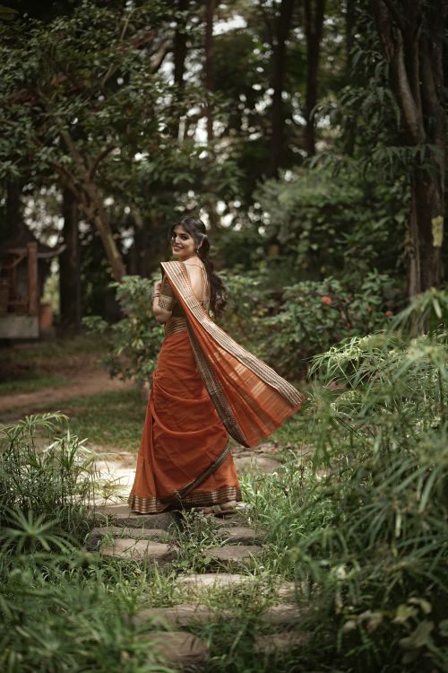 Free Woman in traditional sari walking on a forest path, embracing nature's beauty. Stock Photo