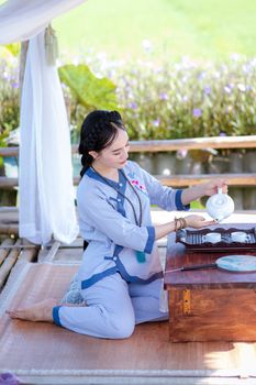 Woman in traditional dress performing a tea ceremony outdoors in Hội An, Vietnam.