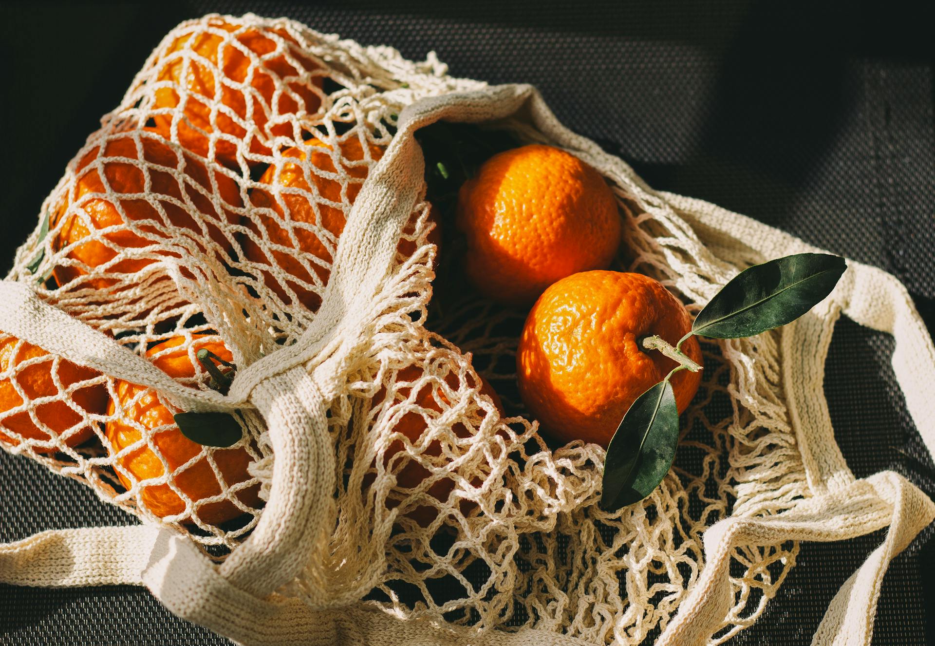 A mesh bag filled with fresh oranges, symbolizing sustainable living and healthy choices.