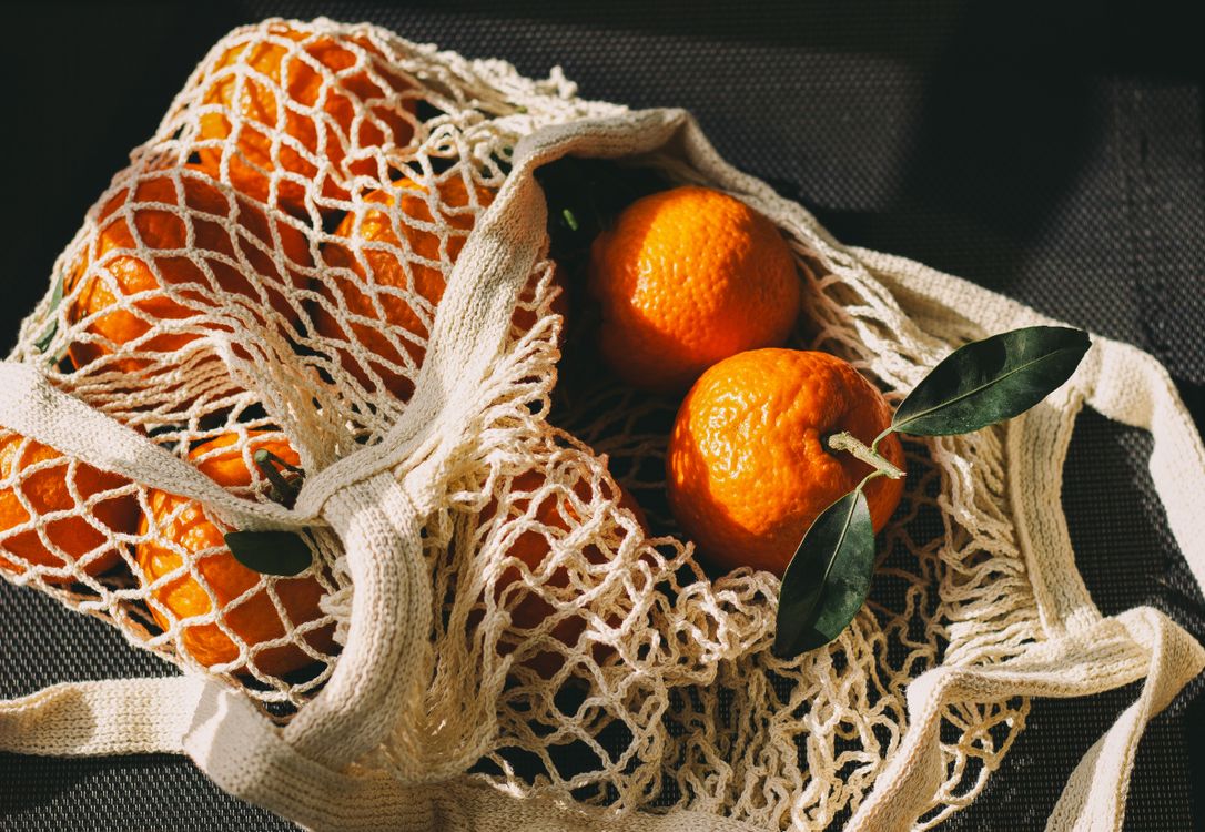 Free A mesh bag filled with fresh oranges, symbolizing sustainable living and healthy choices. Stock Photo