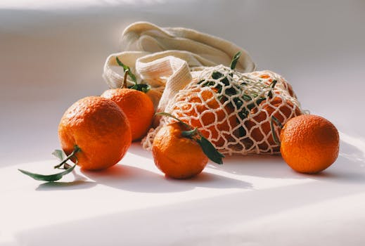 Bright mandarins spill from a reusable mesh bag, basking in natural light.