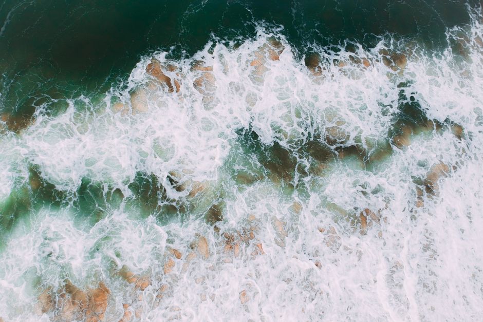 A stunning aerial shot of ocean waves crashing onto a rocky shoreline, showcasing the power of nature.